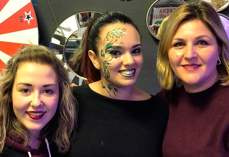 Tres mujeres sonriendo juntas; una de ellas con la cara pintada de verde.