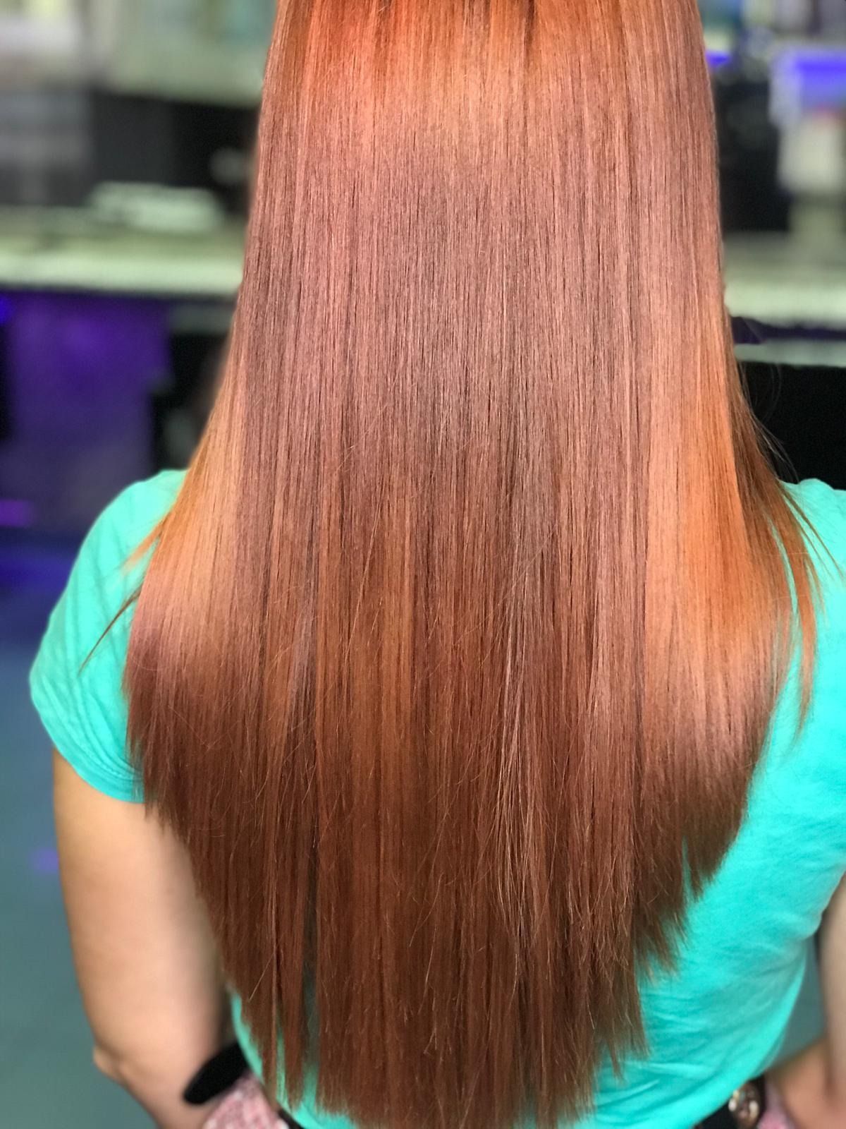 Mujer con cabello largo, liso y de color castaño rojizo, vestida con una camisa verde azulado.