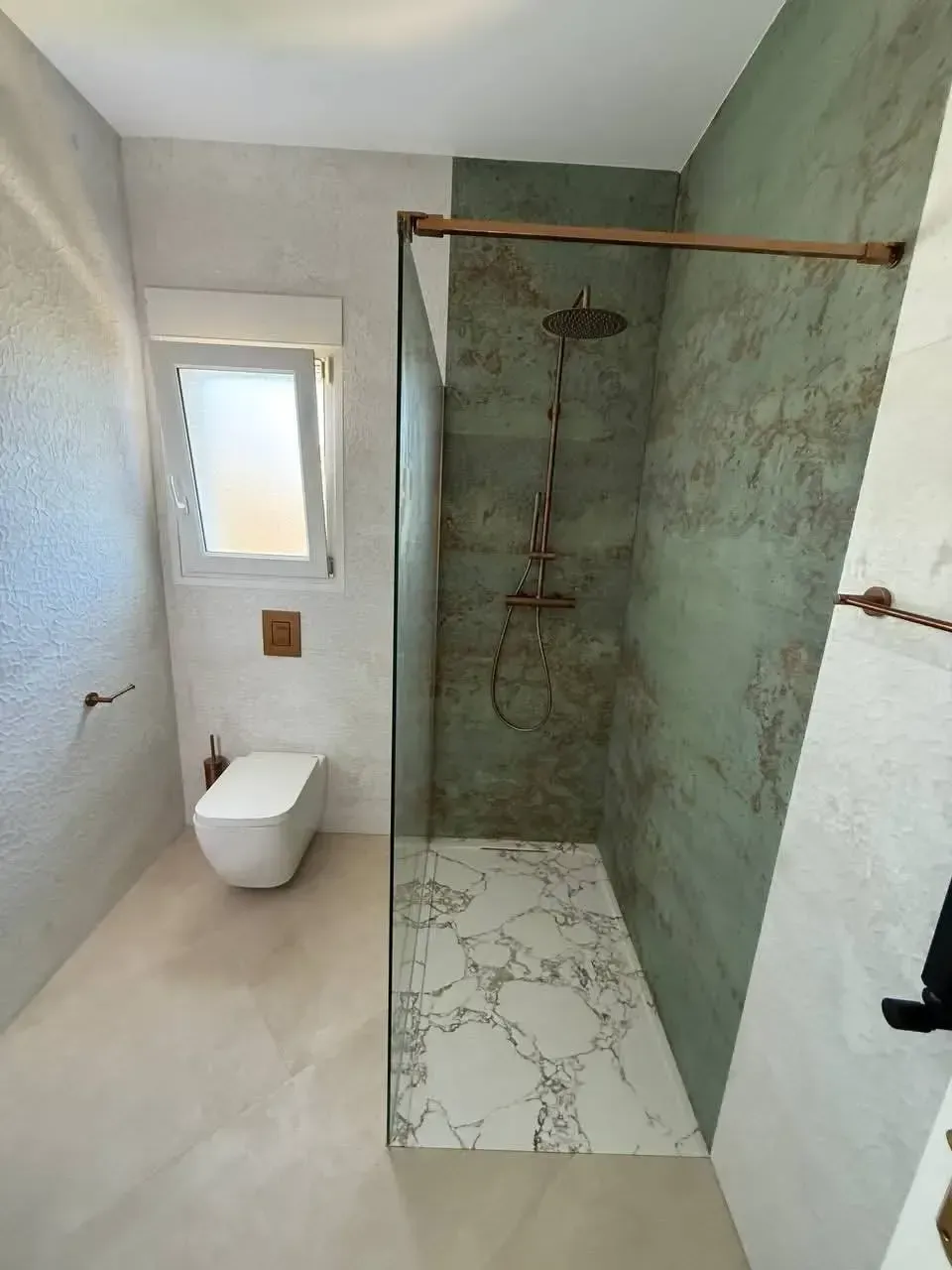 Baño pequeño con ducha a ras de suelo, inodoro suspendido y ventana esmerilada.
