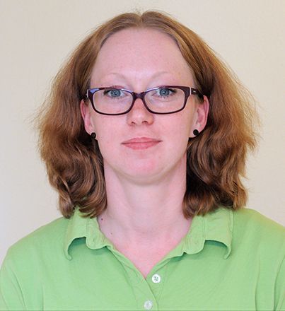 Eine Frau mit Brille und grünem Hemd blickt in die Kamera