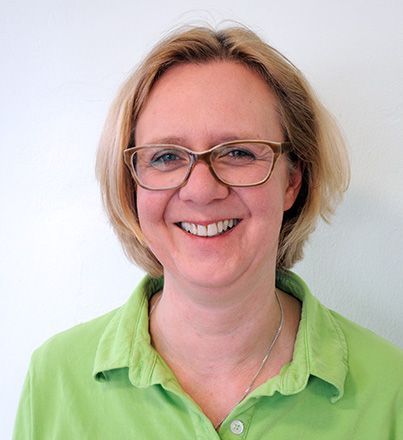 Eine Frau mit Brille und grünem Hemd lächelt in die Kamera