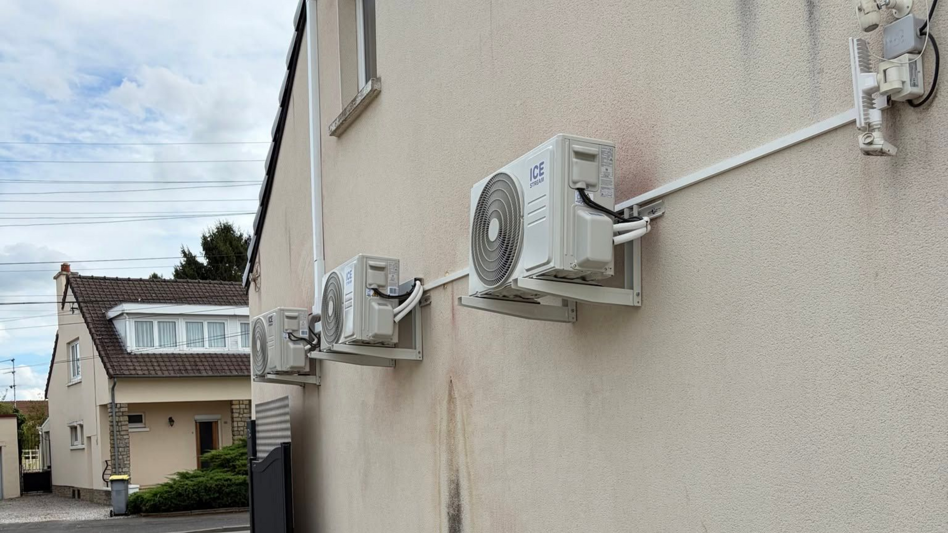 Extérieur d'un bâtiment beige avec plusieurs unités de climatisation fixées le long du mur