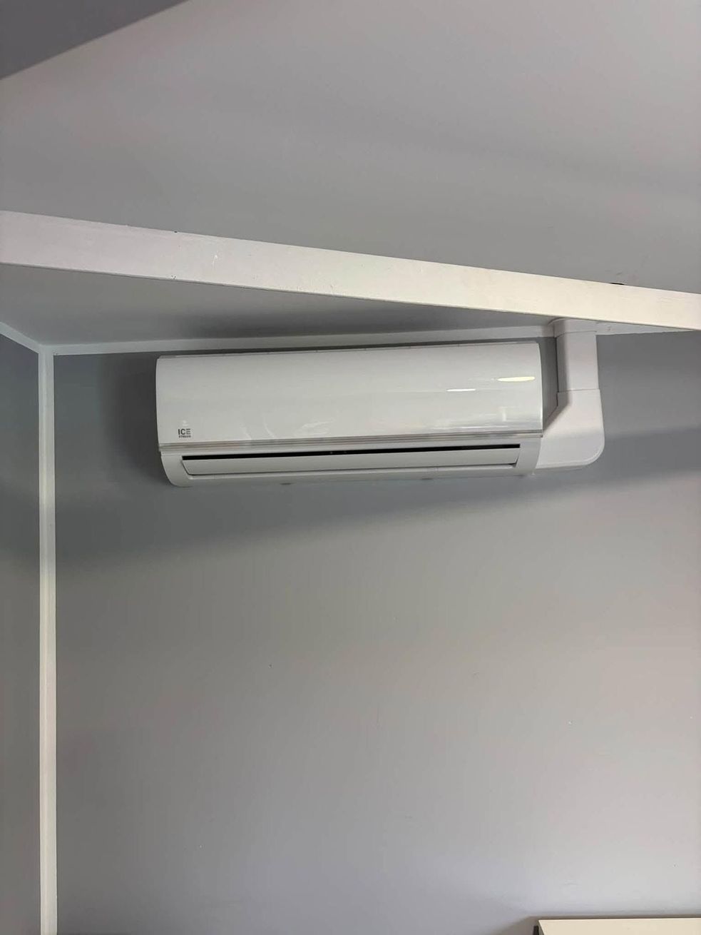 Climatiseur mural blanc près du plafond dans une pièce grise