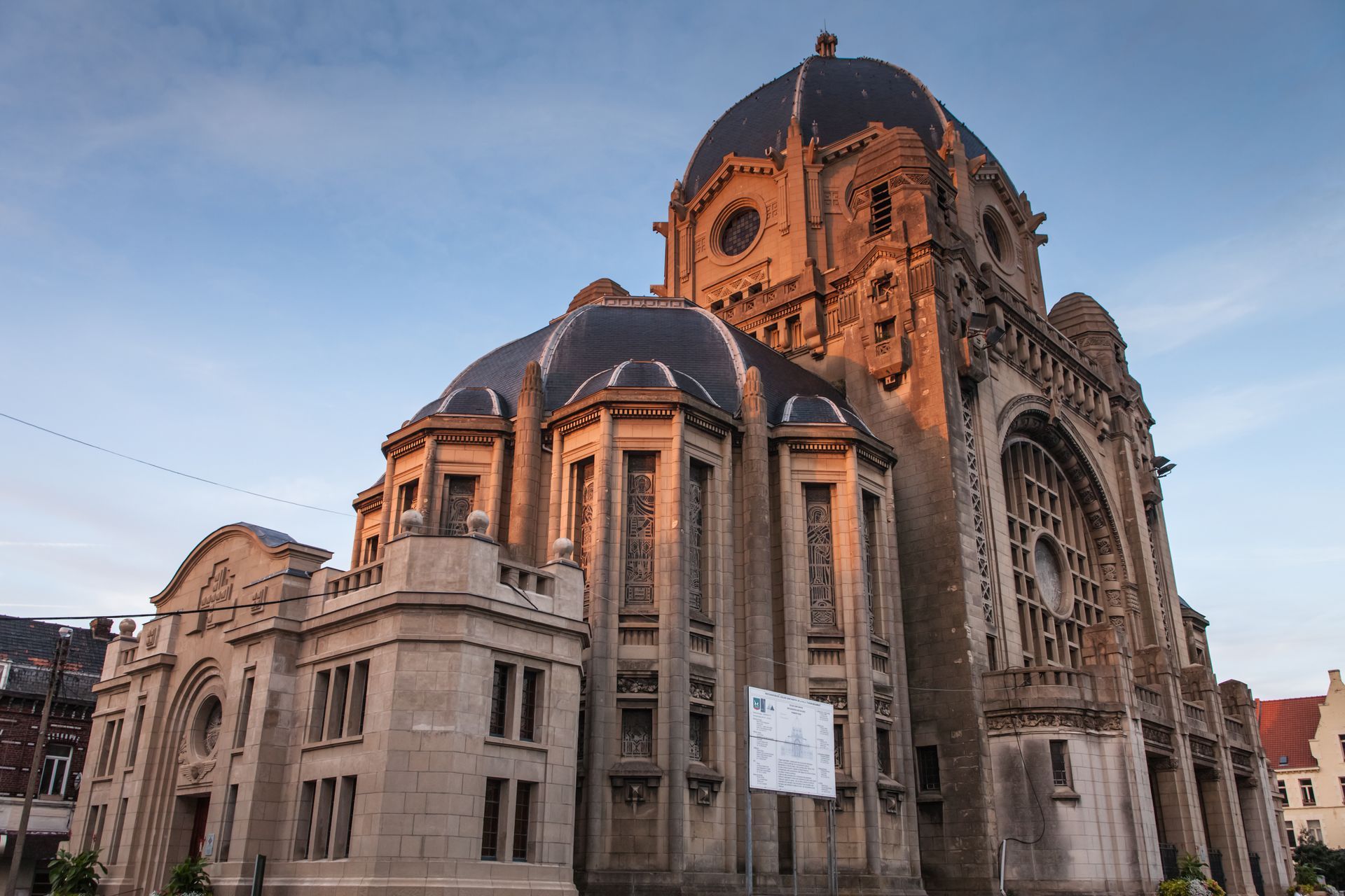 Cathédrale en pierre, avec son toit en dôme et sa façade ornée, au coucher du soleil sous un ciel dégagé.