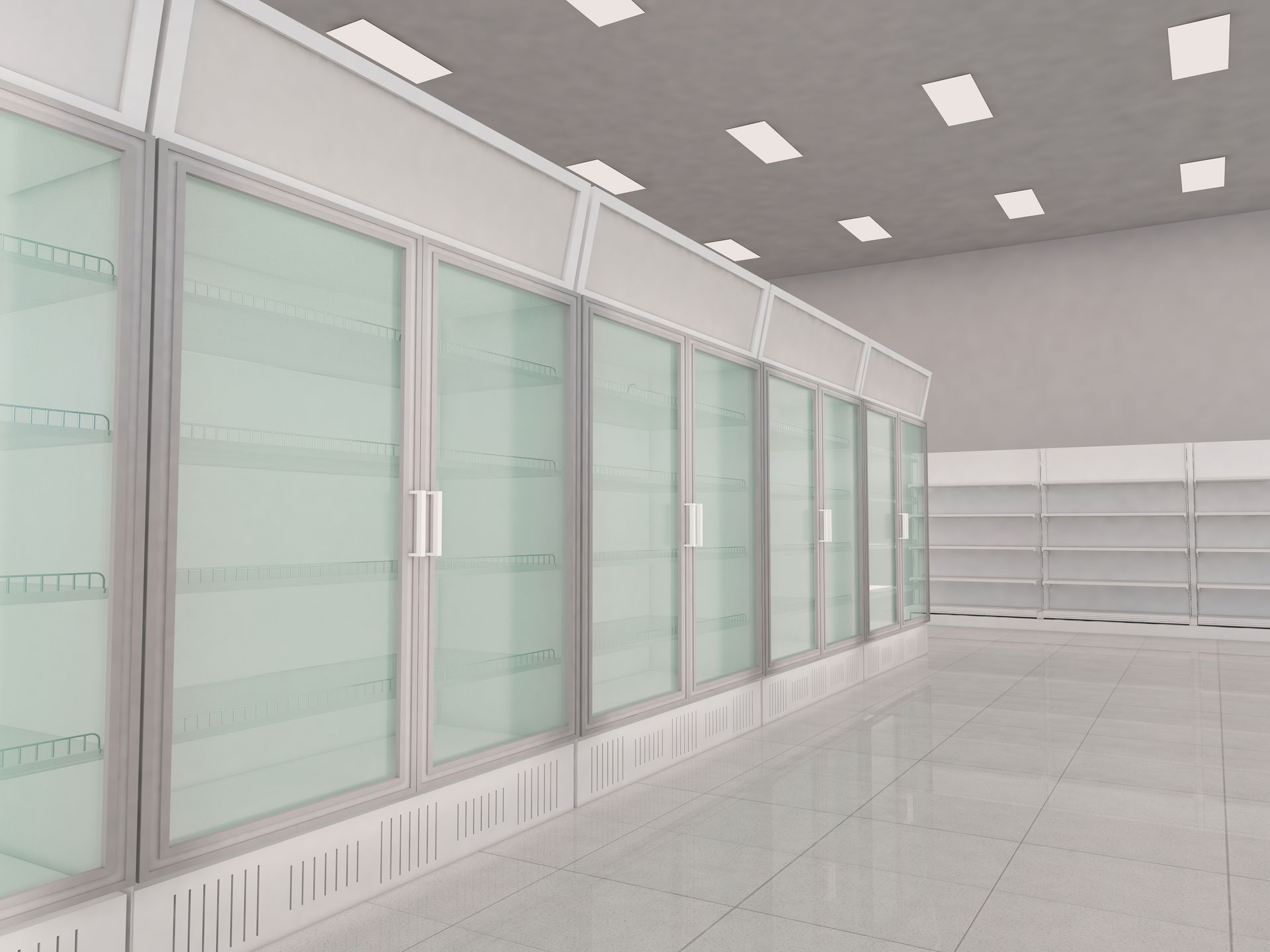 Allée vide d'un magasin moderne, avec des réfrigérateurs à portes vitrées et des étagères blanches éclairées par des plafonniers lumineux.