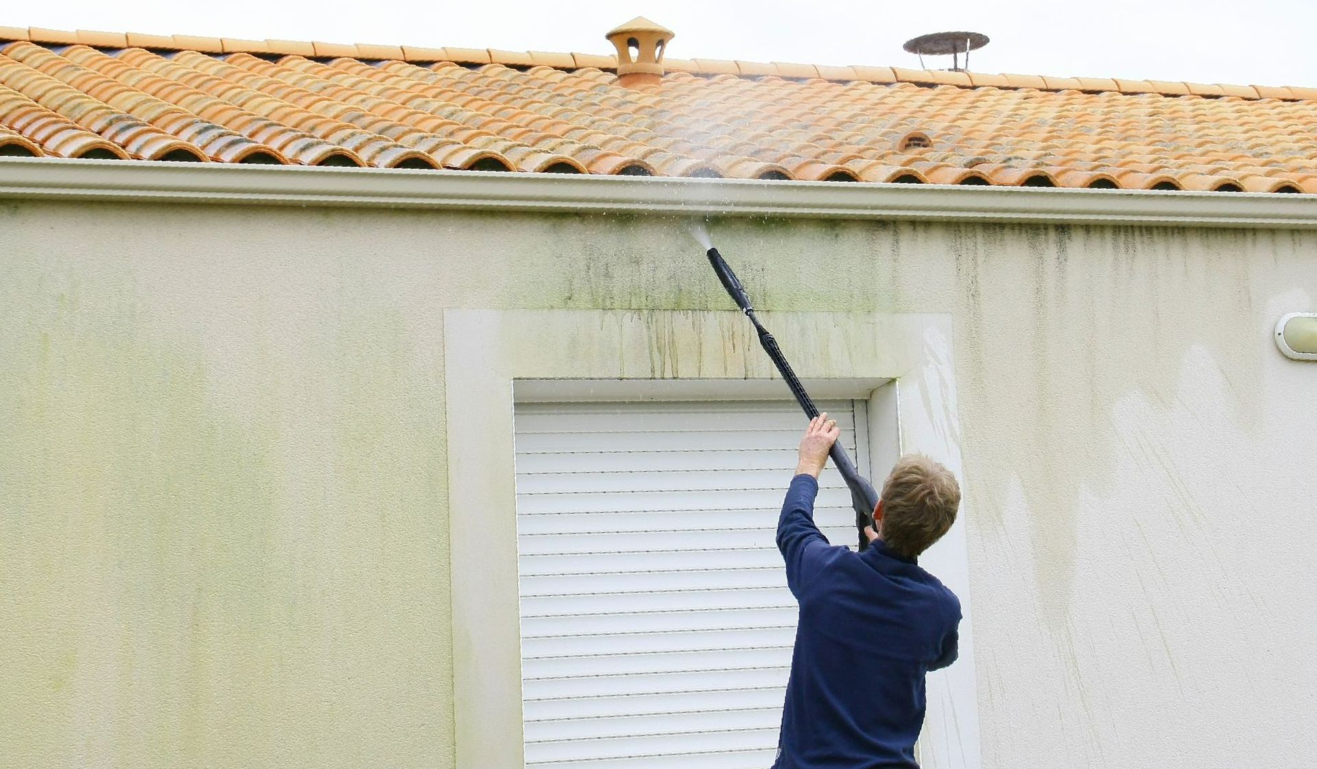 Un homme de dos en train d’émousser un rebord de toiture