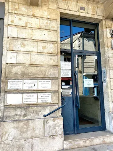 Porte vitrée à cadre bleu dans une façade d'immeuble en pierre, avec de petits panneaux d'affichage à côté.