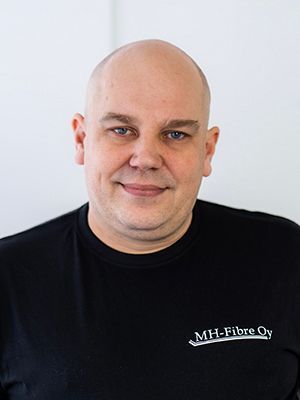 Muotokuva kaljusta miehestä mustassa paidassa valkoista taustaa vasten
