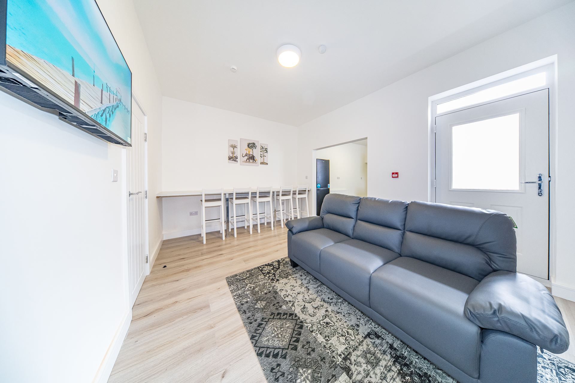 A living room with a couch , chairs , and a flat screen tv.