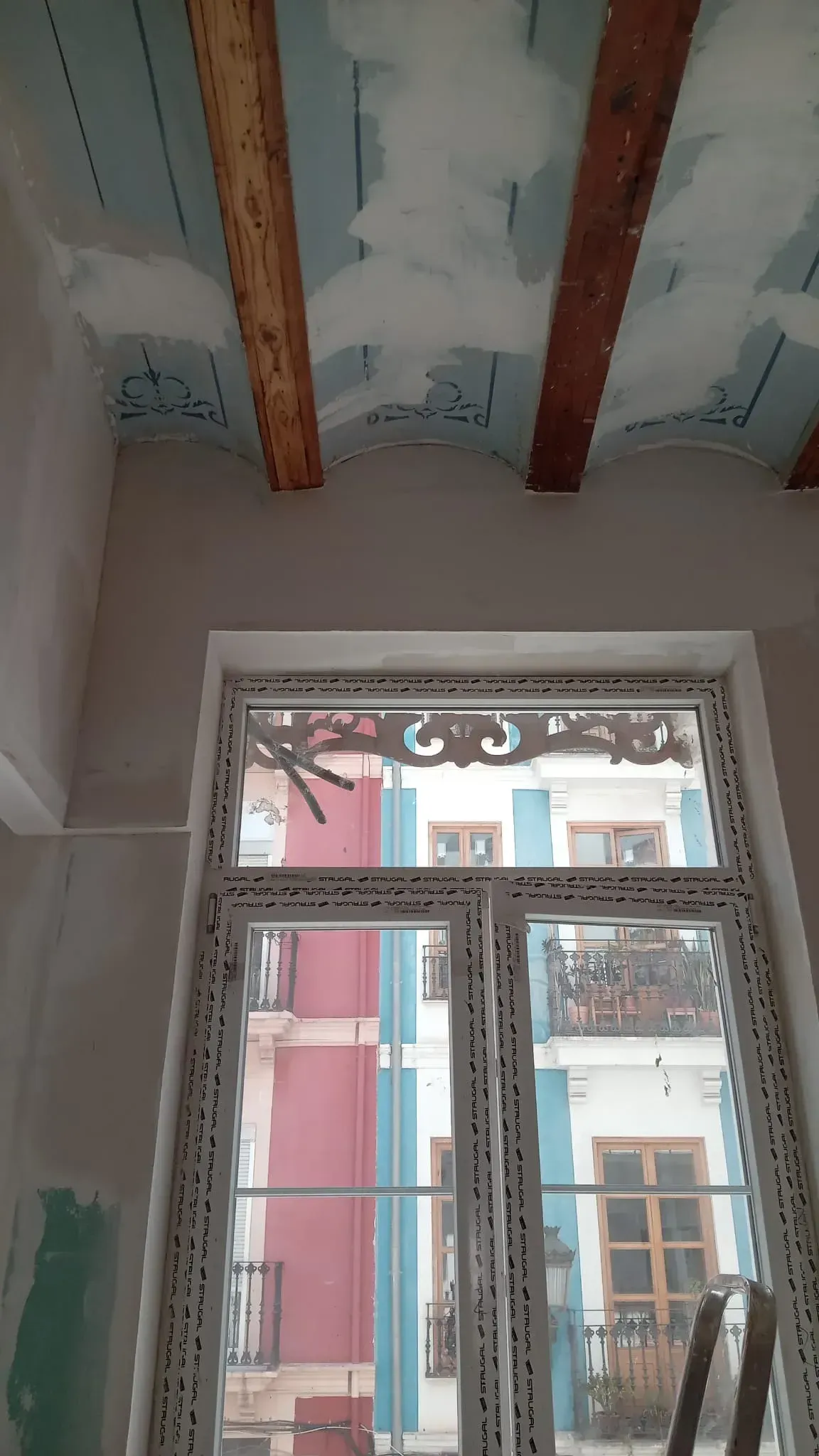 Habitación interior con vigas de madera a la vista en el techo y una gran ventana