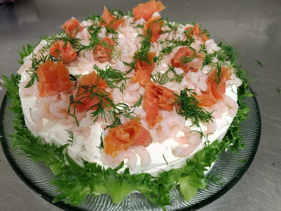 Kalasalaatti lasilautasella, koristeltuna tillillä ja lohella salaatinlehdillä