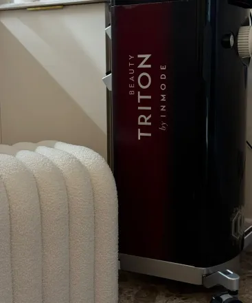Un dispositivo Beauty Triton negro y rojo de Inmode junto a un objeto de espuma blanca.