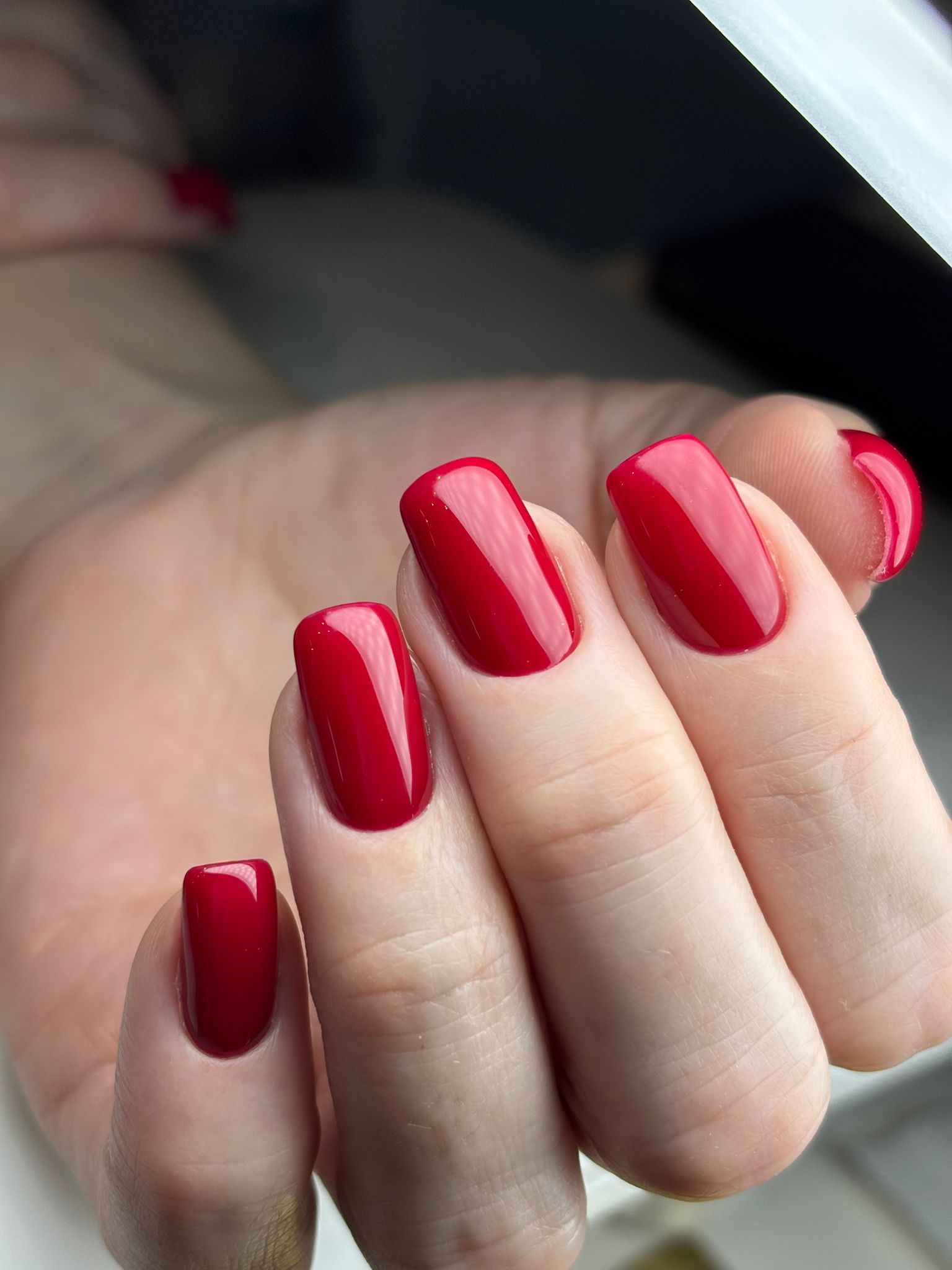 Mano con uñas cuidadas, rojas y de forma cuadrada.