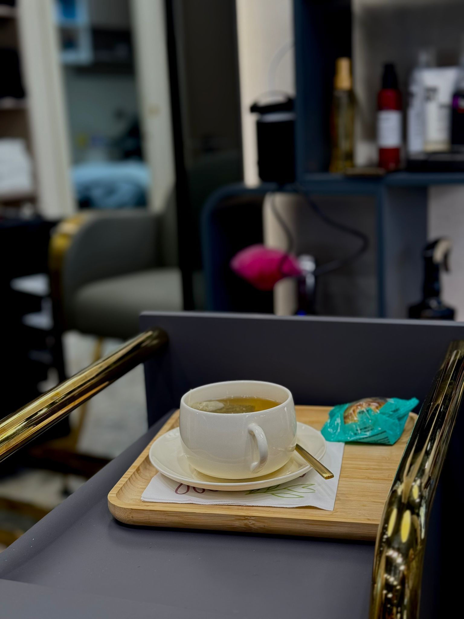 Taza de té en una bandeja de madera con un refrigerio, colocada en un salón con una silla al fondo.