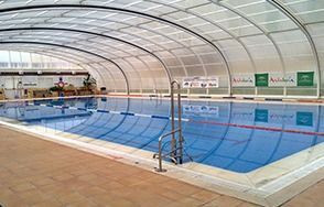 Una gran piscina cubierta bajo un techo transparente.