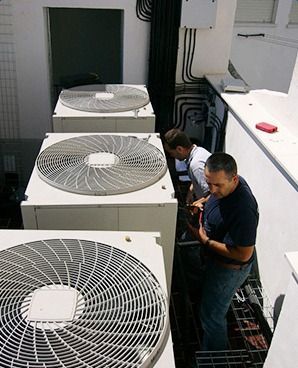 Un grupo de hombres está trabajando en un sistema de aire acondicionado.