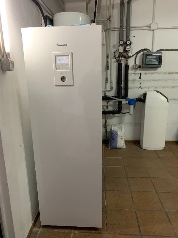 Un refrigerador blanco está en una habitación al lado de una pared.