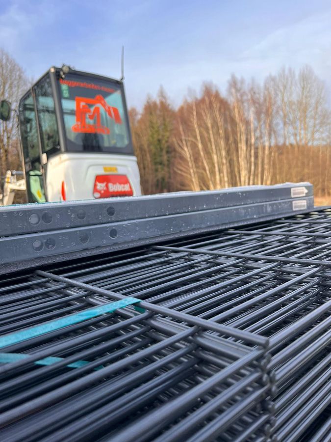 ein Stapel Drahtzäune mit einem Bulldozer im Hintergrund.