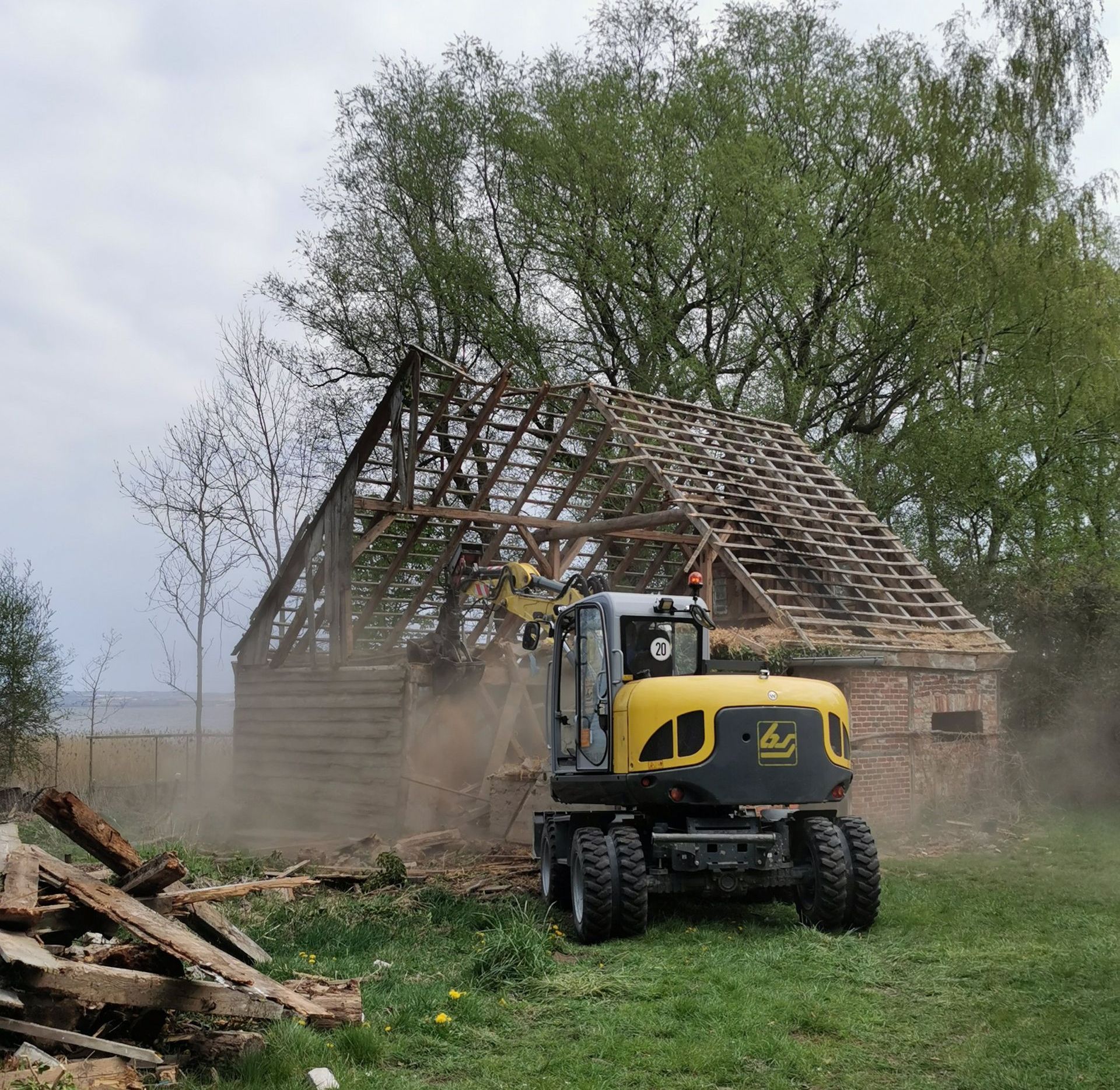 Ein Bagger der ein Holzgerüst abreißt