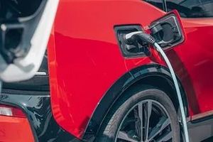 Un coche eléctrico rojo se está cargando en una estación de carga.
