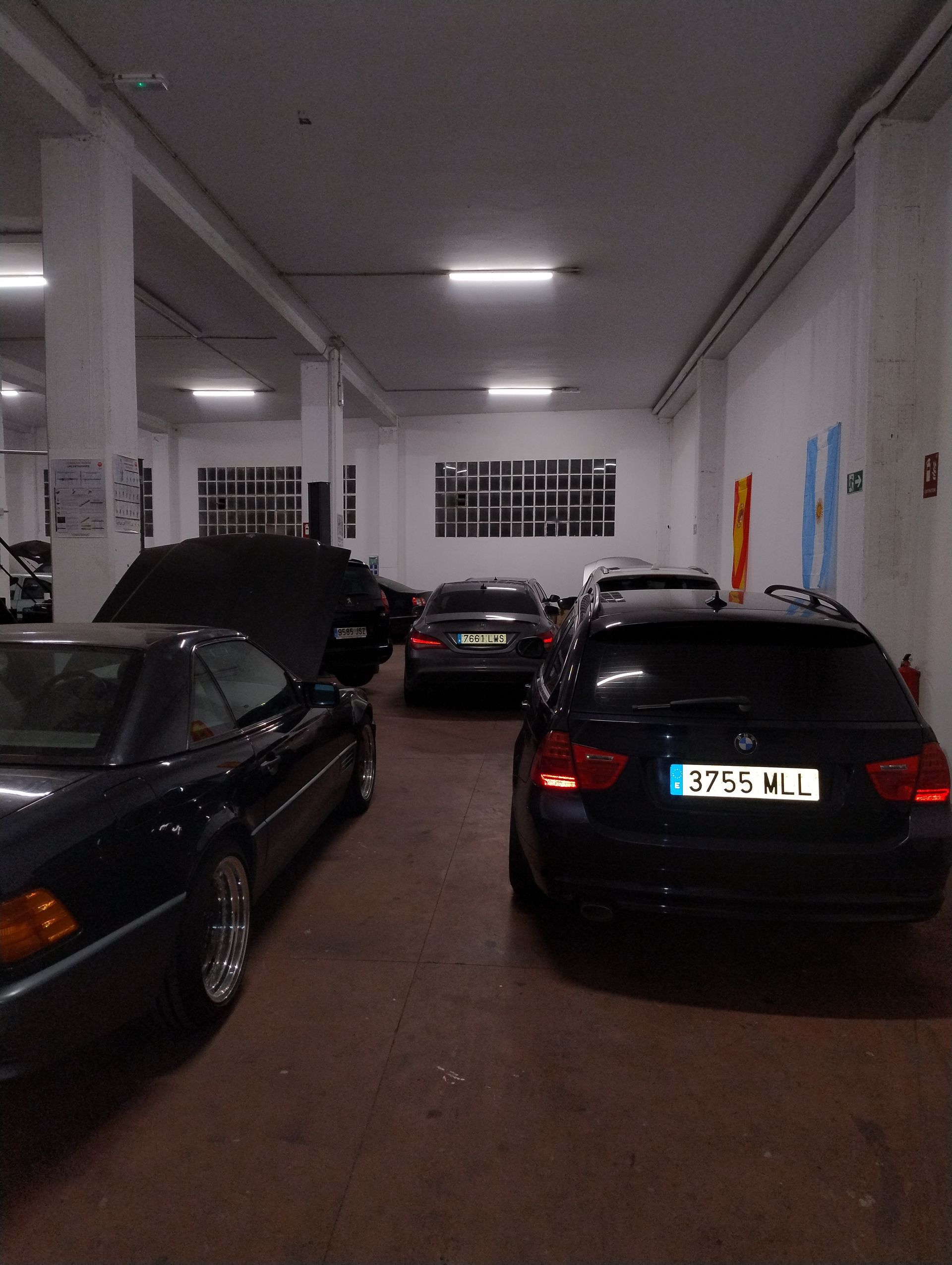 Una fila de autos están estacionados en un garaje y uno de ellos tiene una matrícula que dice jcw-wll