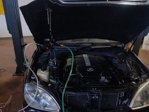 El capó de un coche está abierto y se está trabajando en el motor.
