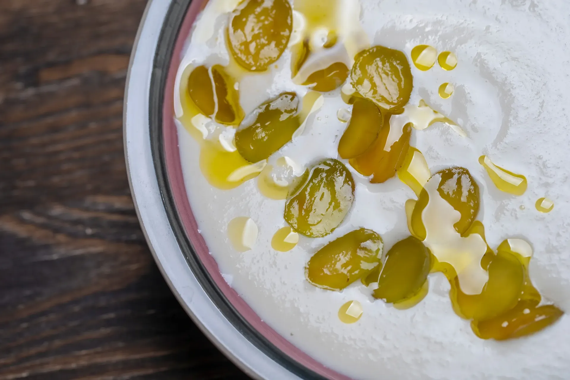 Tazón de yogur blanco, cubierto con pasas doradas y rociado con miel.