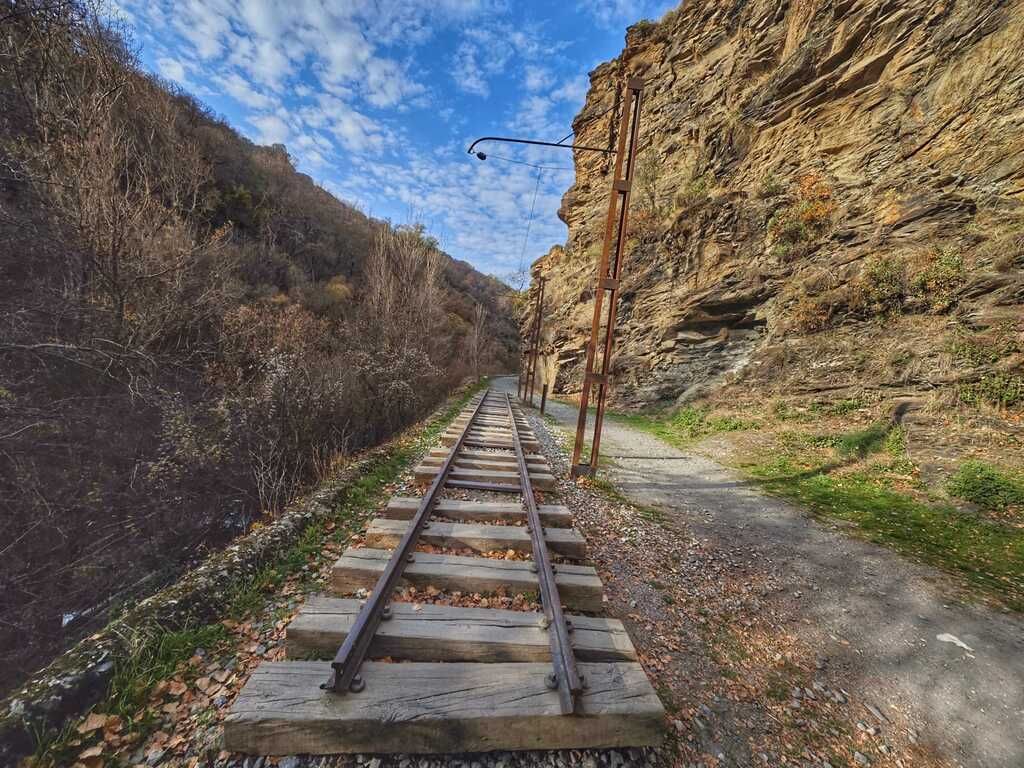Antiguas vías de ferrocarril y un sendero que serpentea a través de un cañón rocoso.