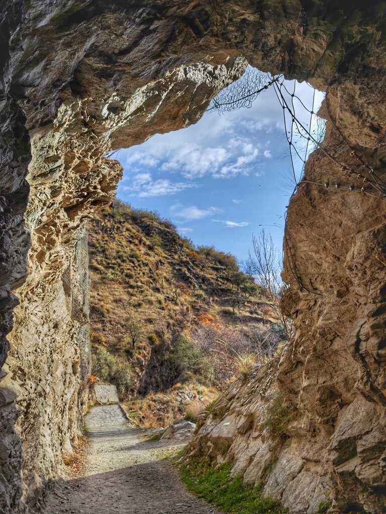 La salida del túnel deja ver un paisaje de cañón, cielo azul con nubes.