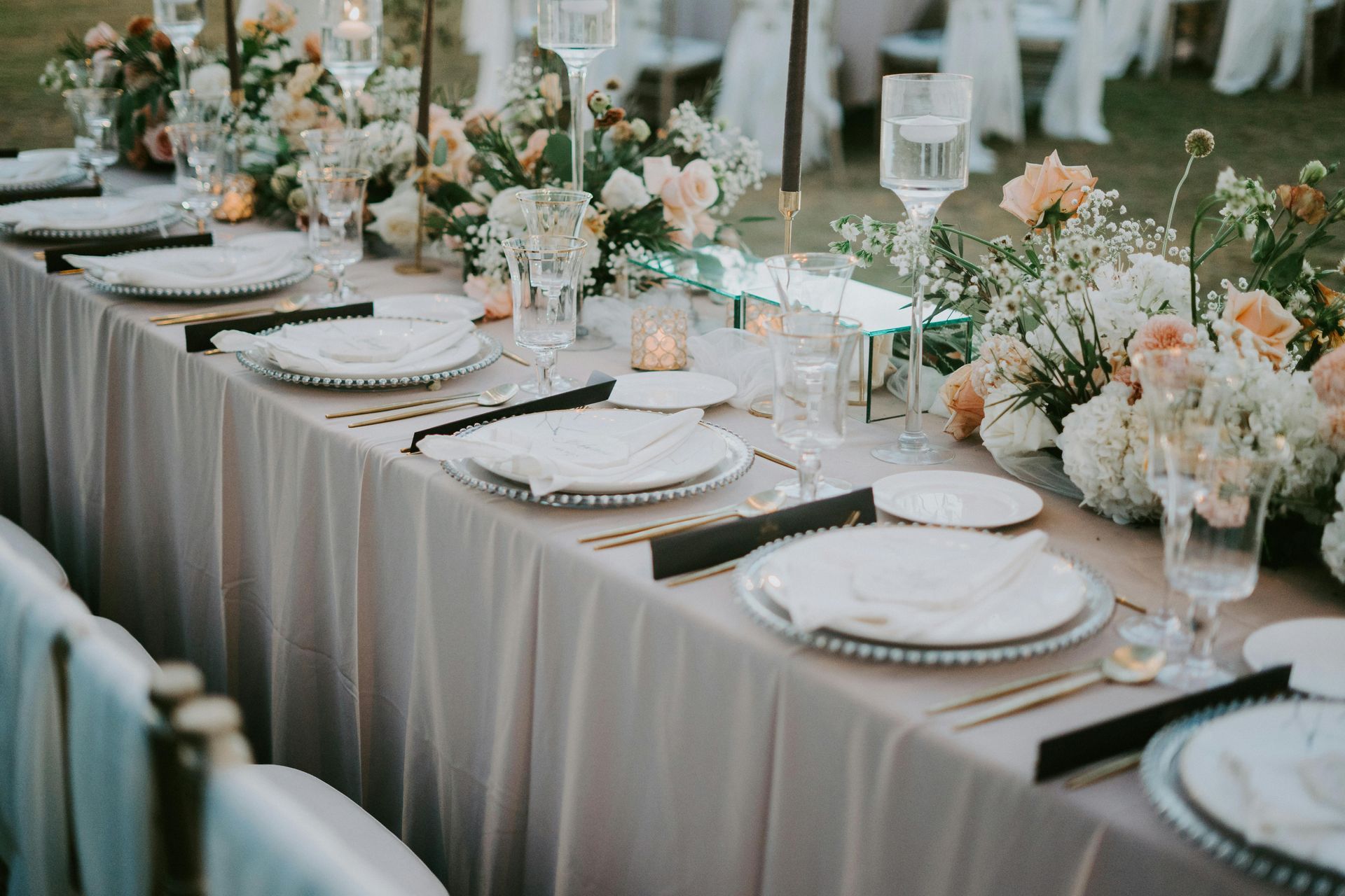 Elegante mesa de recepción de boda con arreglos florales y cubiertos.