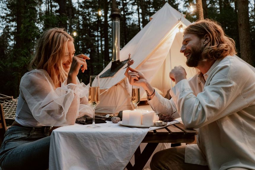 Pareja disfrutando de una cena romántica al aire libre en un camping, 