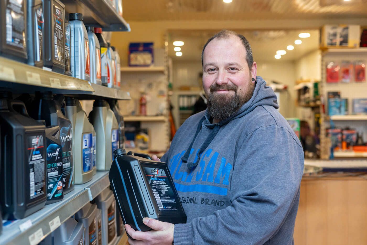 Ein Mann mit Bart hält in einem Geschäft eine Schachtel.