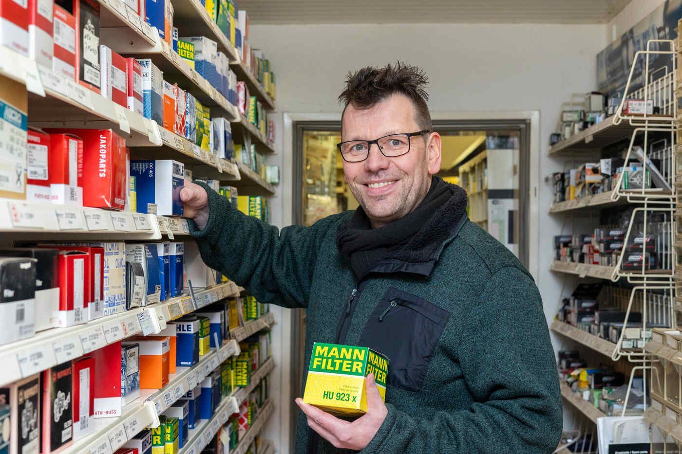 Ein Mann steht in einem Geschäft und hält einen Filter in der Hand.