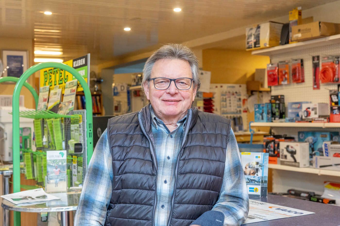 Ein Mann mit Brille und Weste steht in einem Geschäft.