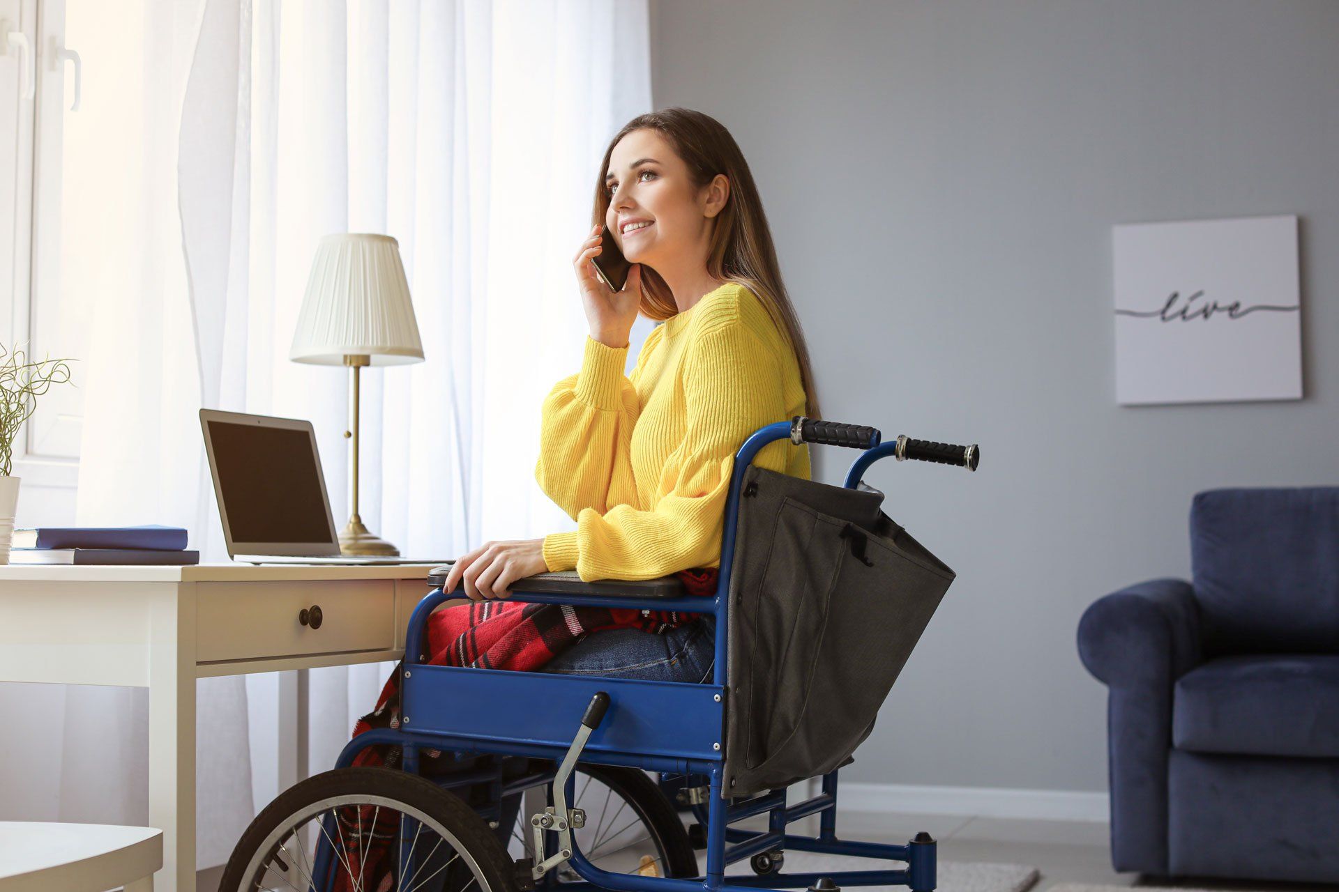 Une femme au téléphone devant son bureau dans un fauteuil roulant