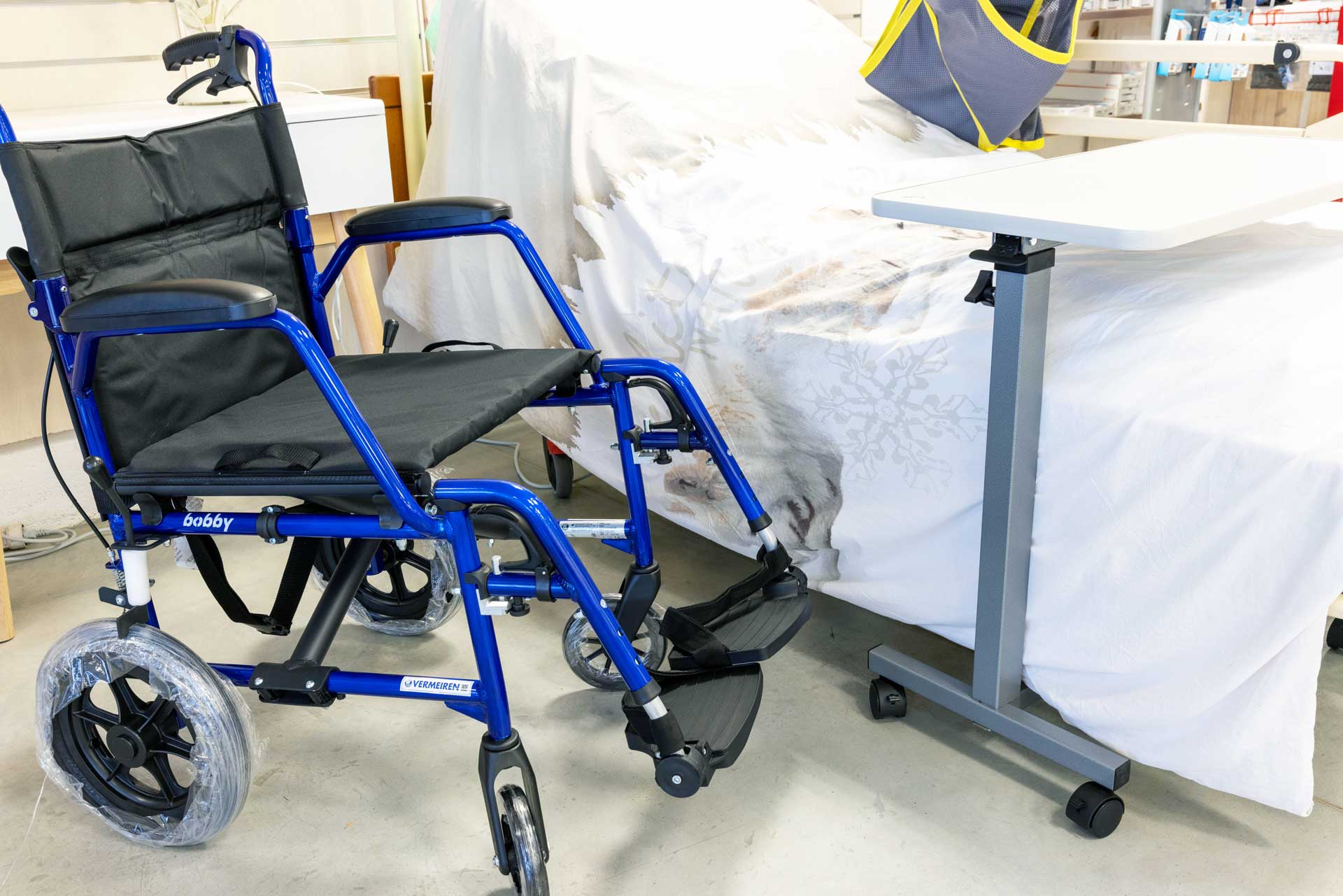 Un fauteuil roulant devant un lit médicalisé dans un des magasins Sérédom