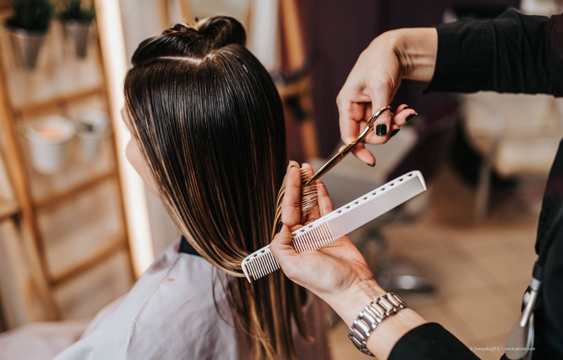 Eine Friseurin schneidet einer Kundin in einem Salon mit Schere und Kamm die nassen Haare.