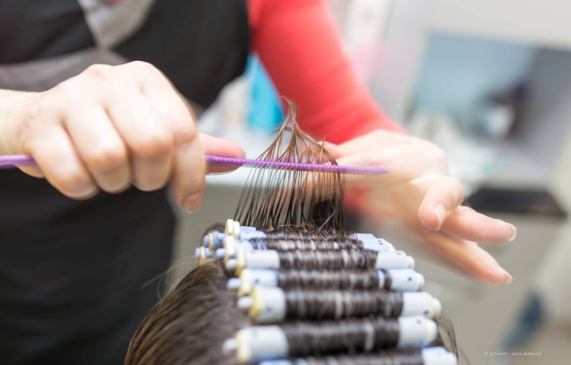 Friseurin kämmt und dreht Haare in Lockenwickler.