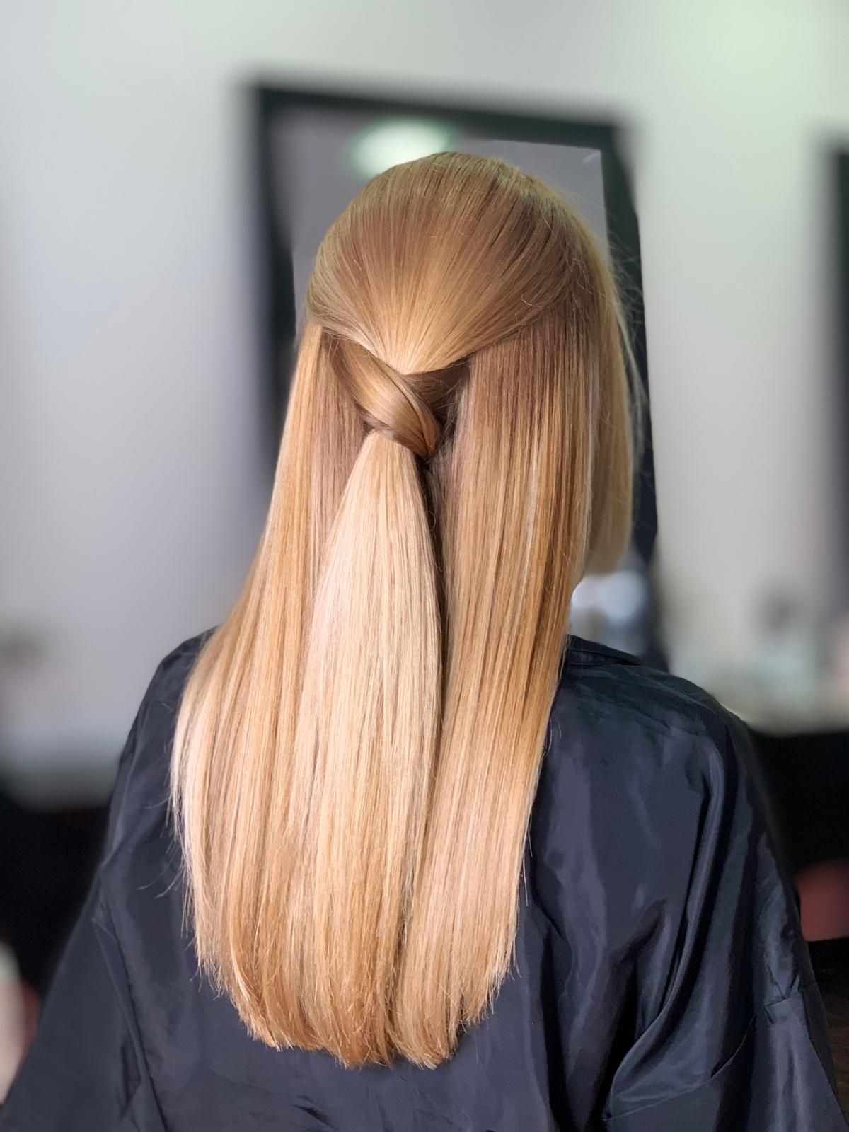 Mujer con cabello largo, rubio y liso, peinado con un giro en la parte posterior.