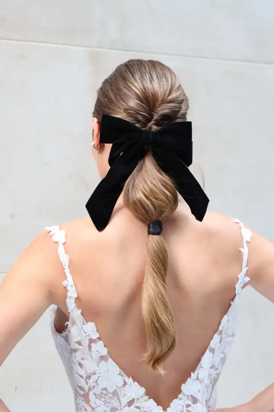 Mujer con cabello rubio recogido, con un lazo de terciopelo negro y un vestido de encaje blanco.