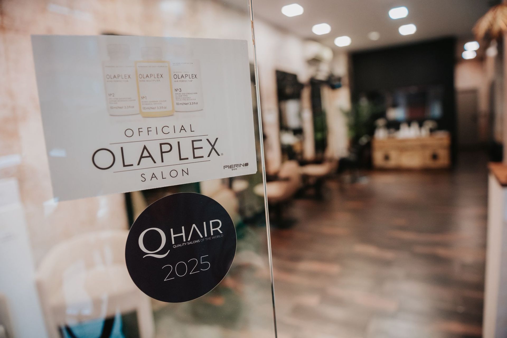 Entrada de un salón con un cartel de Olaplex y una pegatina de 