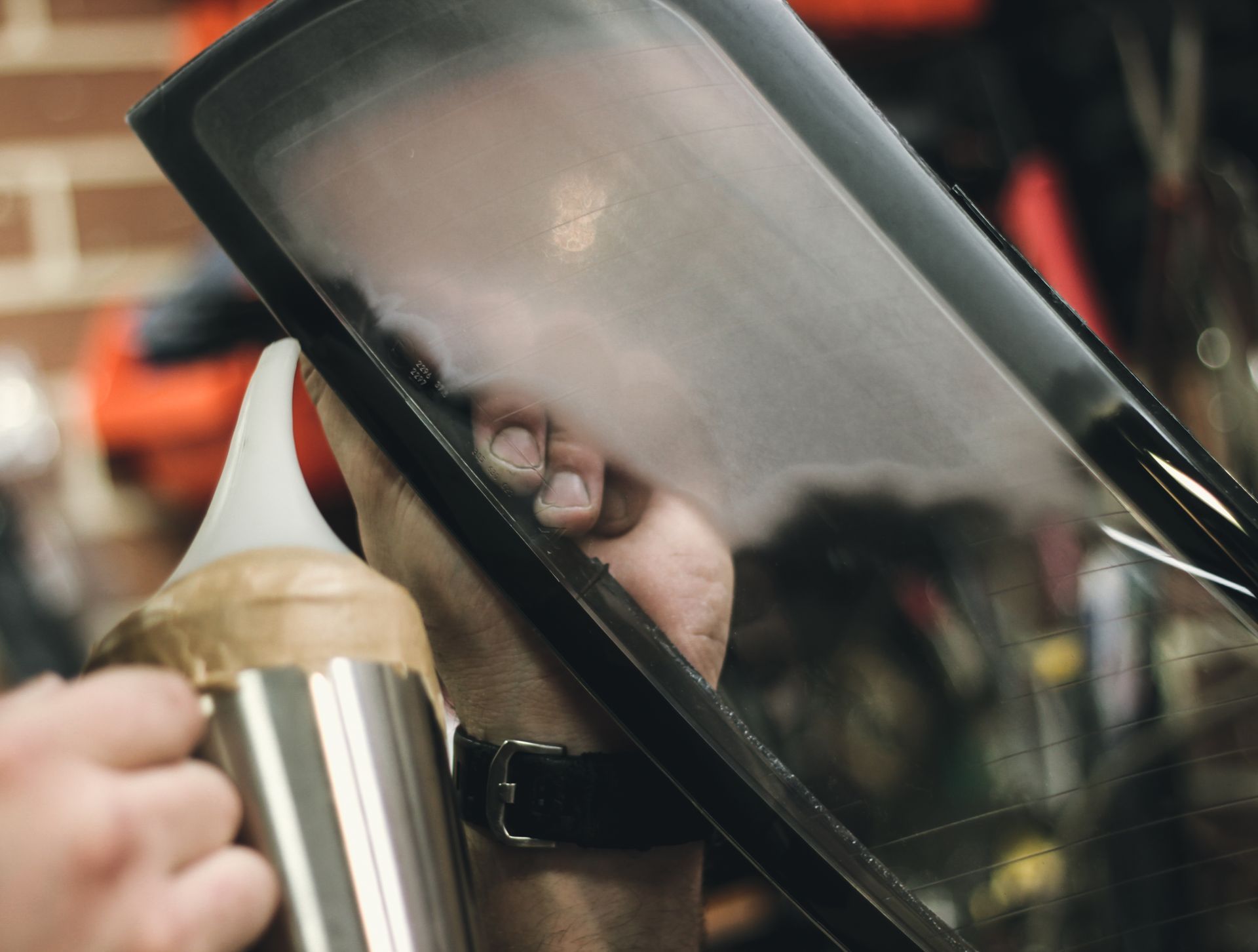 Une main applique de la colle sur un pare-brise