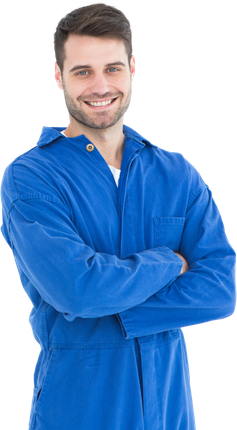 Un homme en salopette de travail bleue sourit, les bras croisés.