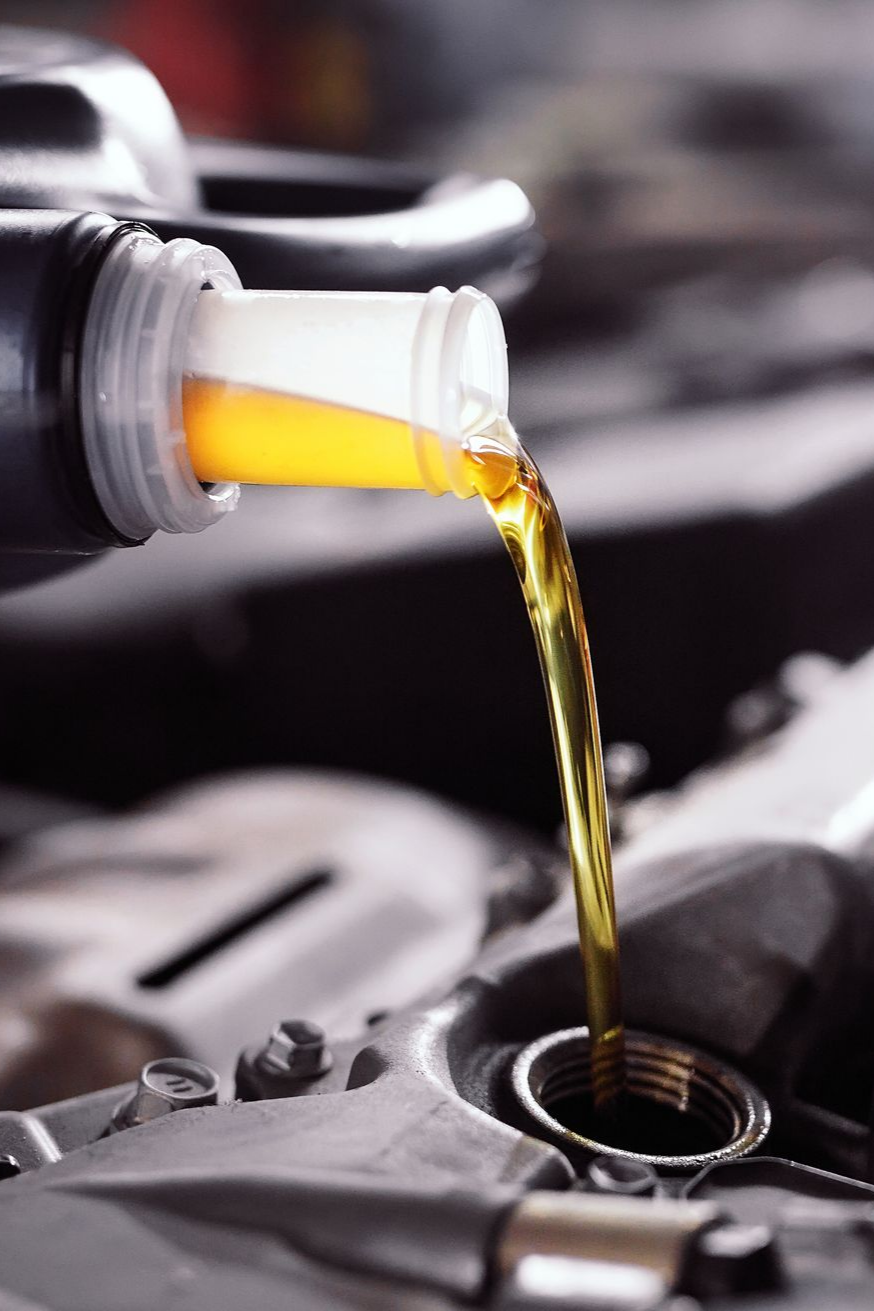 Versement d'huile moteur dans un moteur de voiture, liquide jaune s'écoulant d'une bouteille.