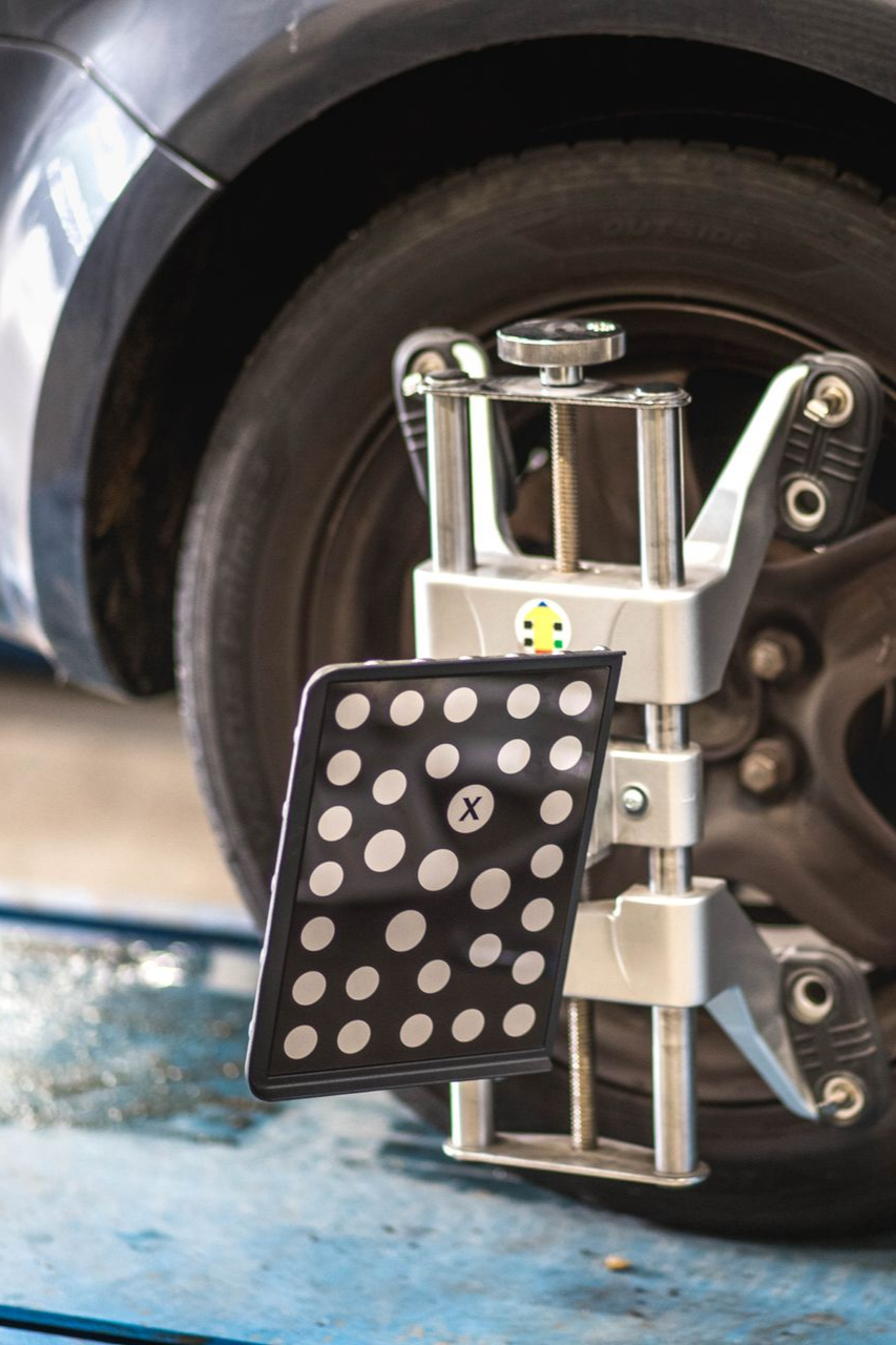 Roue de voiture équipée d'un appareil d'alignement, mesurant les angles.