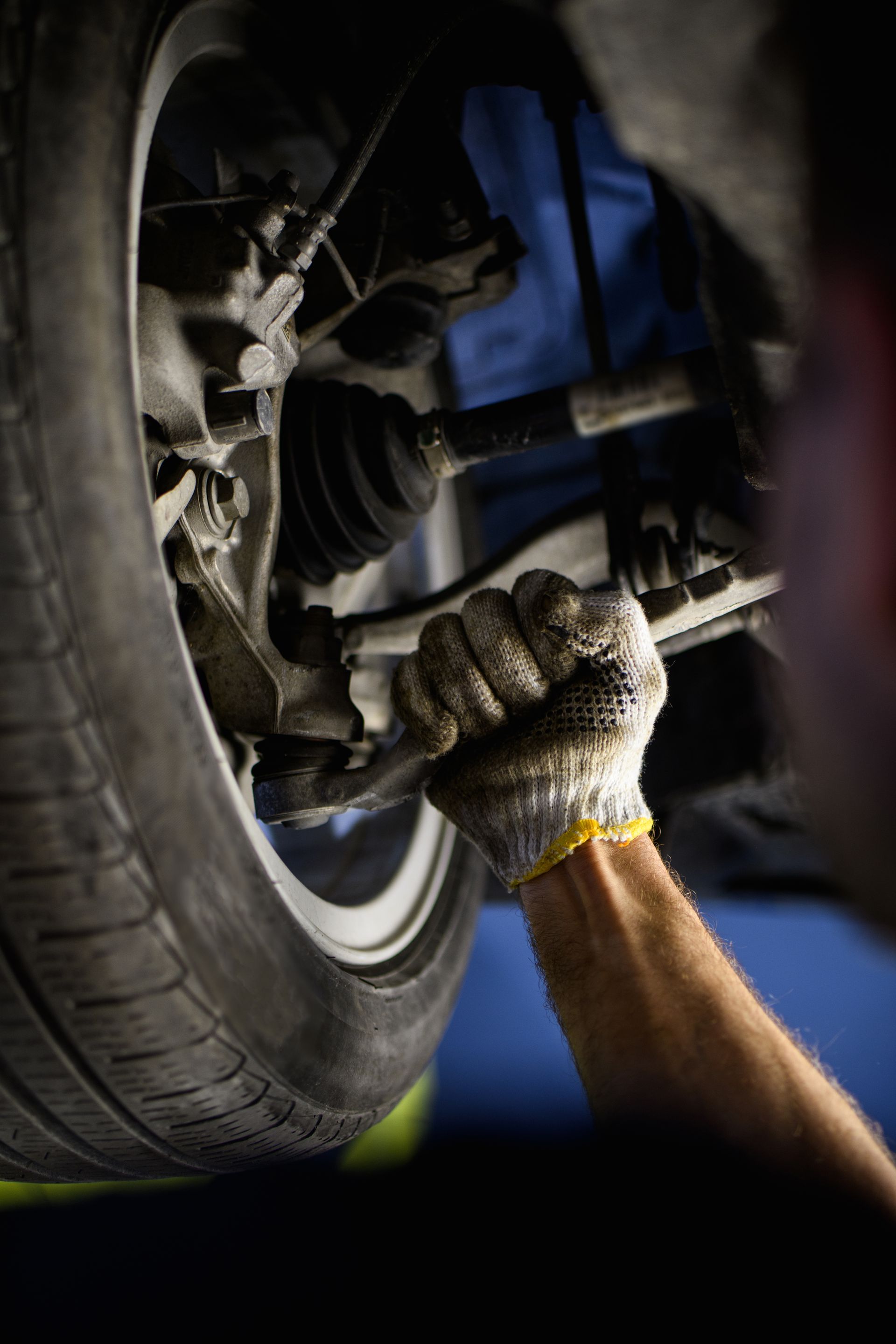 Main gantée d'une personne travaillant sur une roue de voiture.