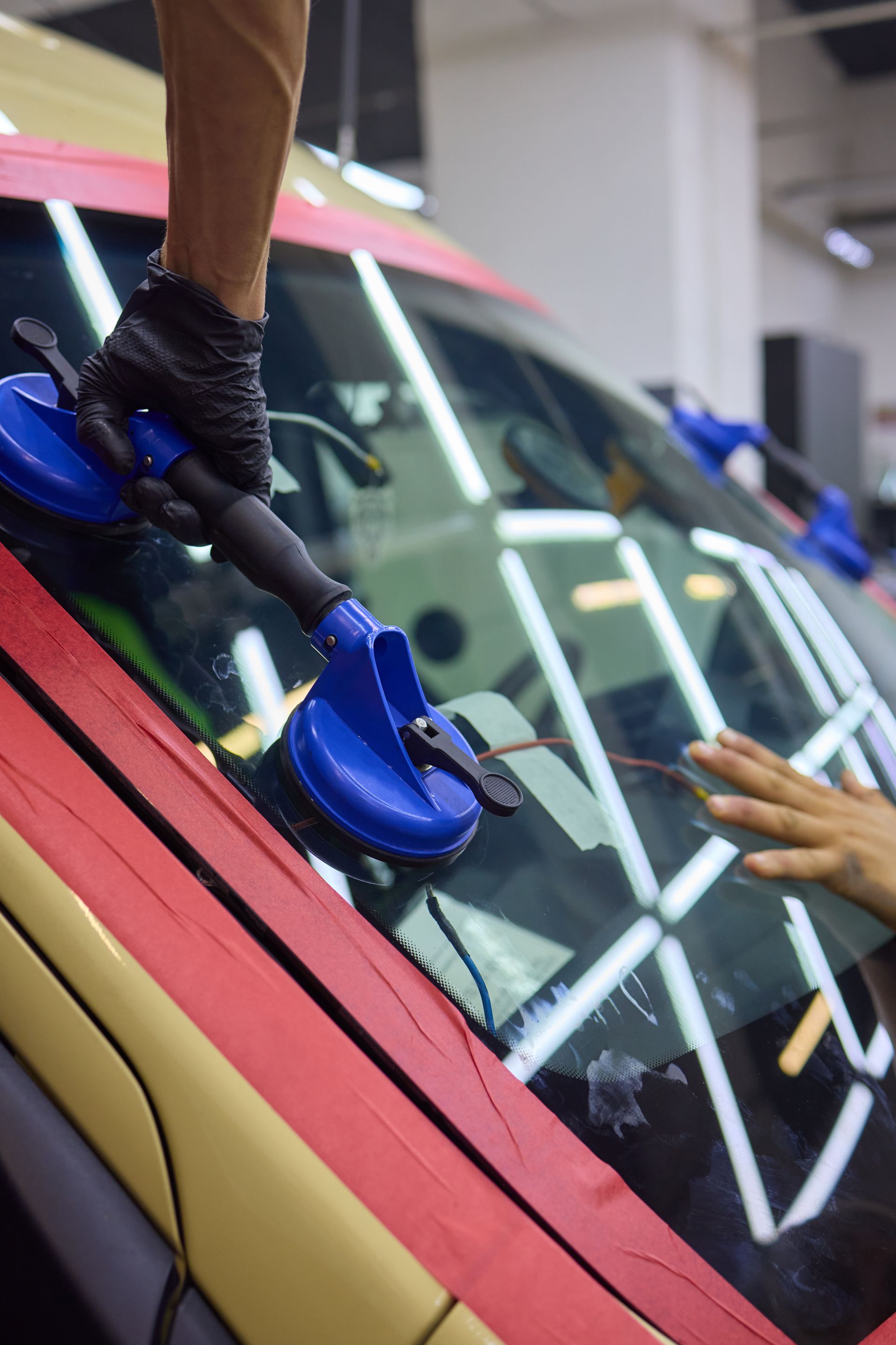Une personne utilise une ventouse bleue pour retirer un pare-brise d'un véhicule.