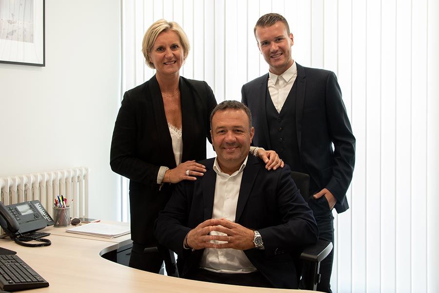 Trois avocats qui prennent la pose derrière un bureau.