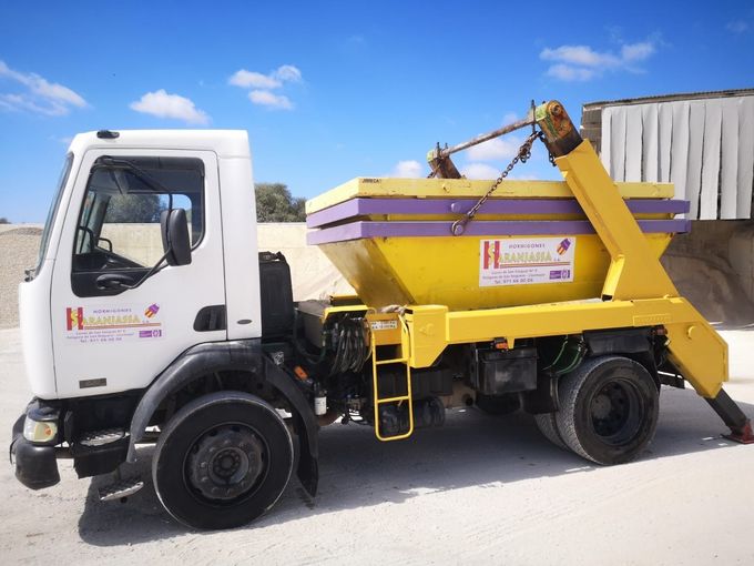Un camión volquete amarillo y morado está estacionado al costado de la carretera.