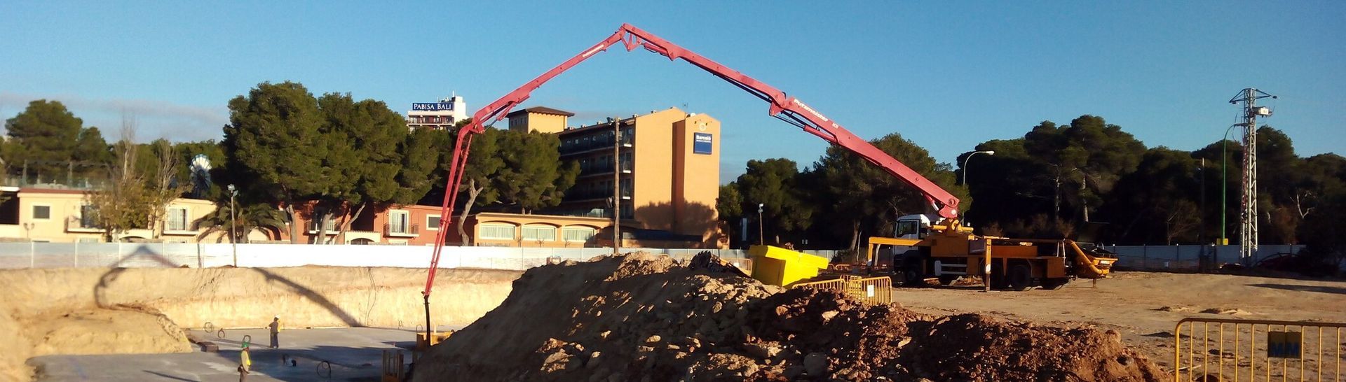Una obra en construcción con un gran montón de tierra y una grúa al fondo.